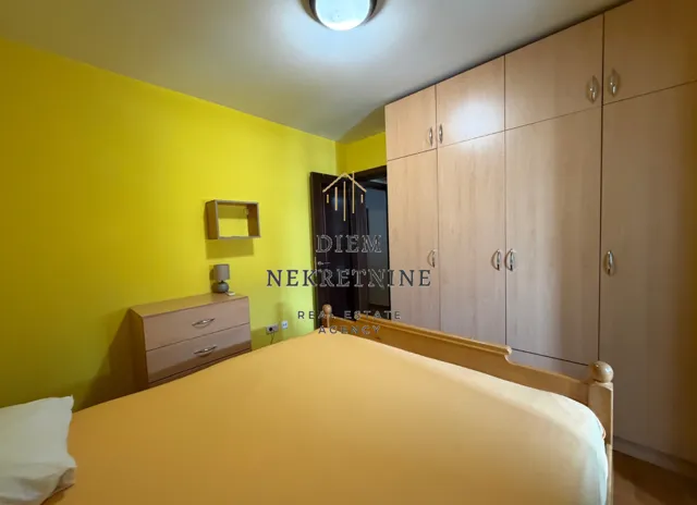 Namještena spavaća soba sa velikim bračnim krevetom i ugradnim plakarom.