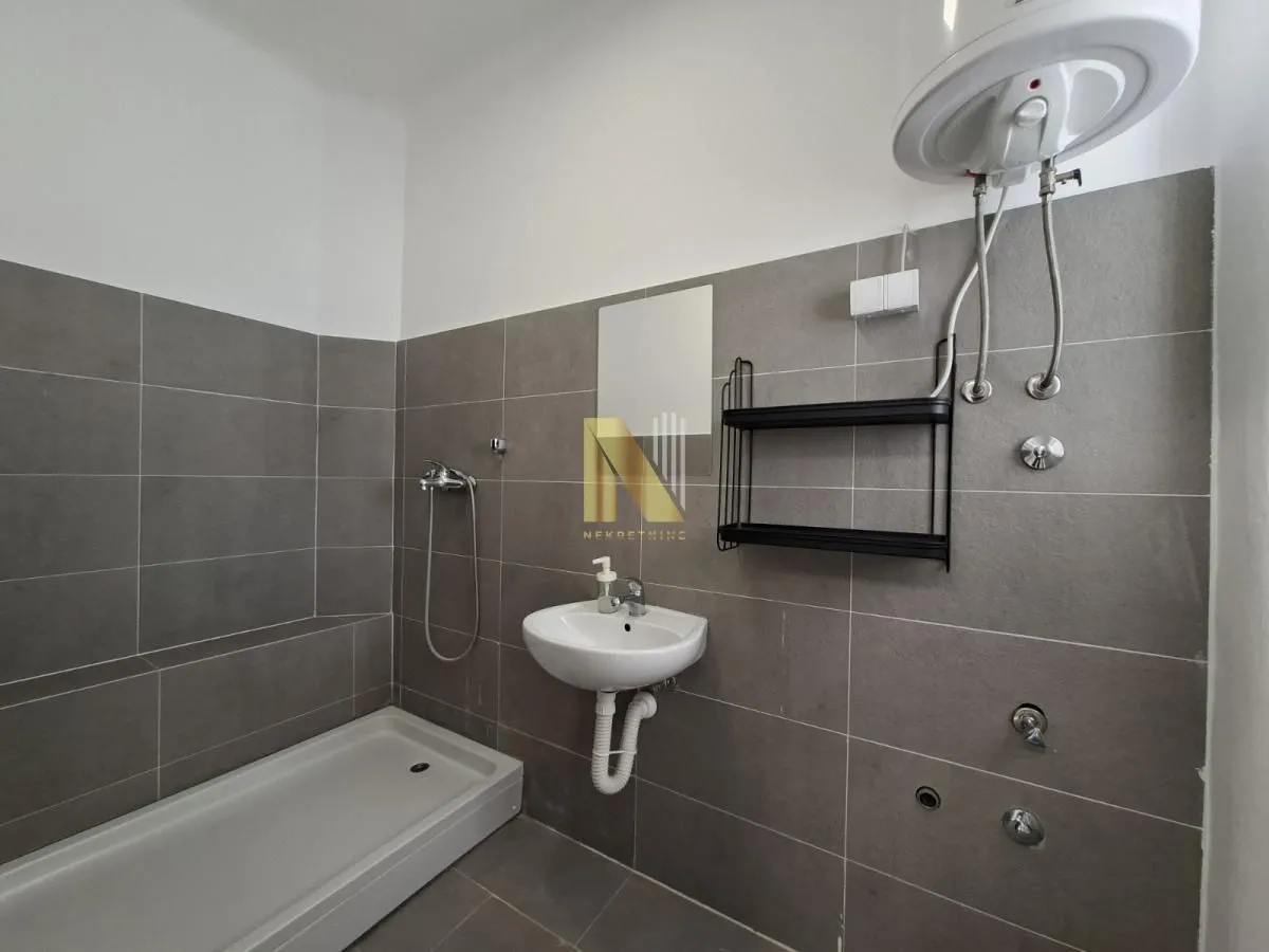 Bathroom with a shower cabin, washbasin, and water heater.