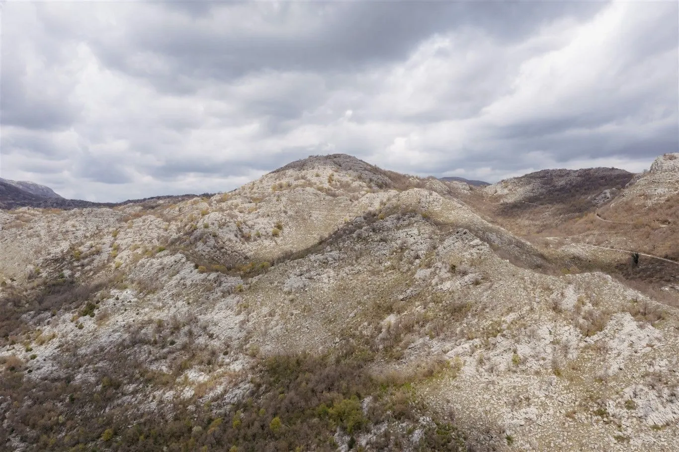 Pogled na krševiti planinski pejzaž pod oblačnim nebom.