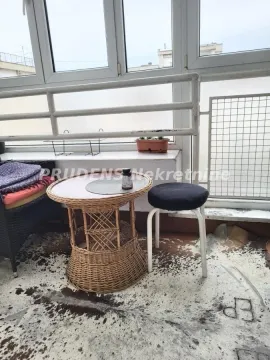 Enclosed balcony with a small wicker table and a stool. - image 18