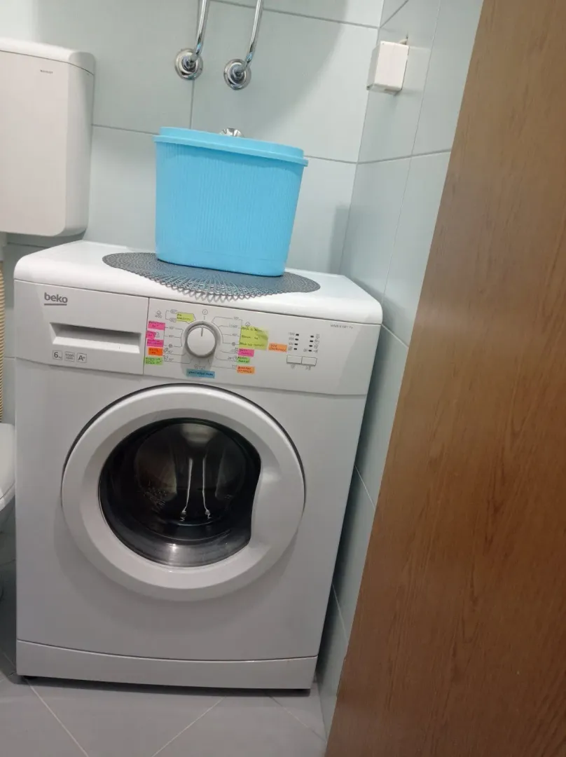 Washing machine in a bathroom with blue tiles.