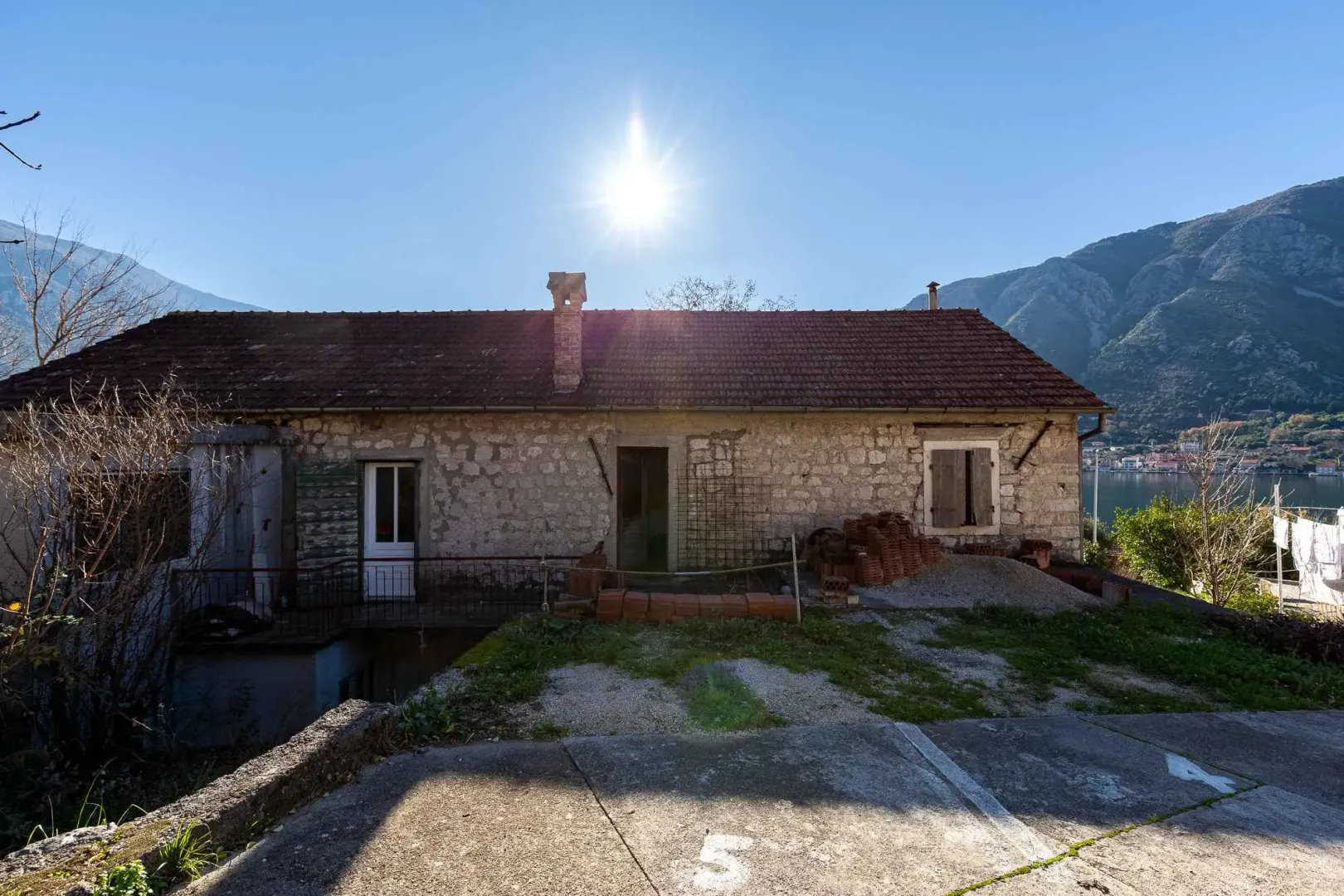 Pogled na stari kameni objekat sa dvorištem i pogledom na more u pozadini.