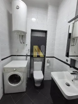 Manje kupatilo obloženo belim pločicama sa tuš kabinom, umivaonikom i veš mašinom. - image 10