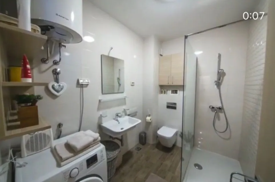 Compactly equipped bathroom with a walk-in shower, washbasin, and washing machine.