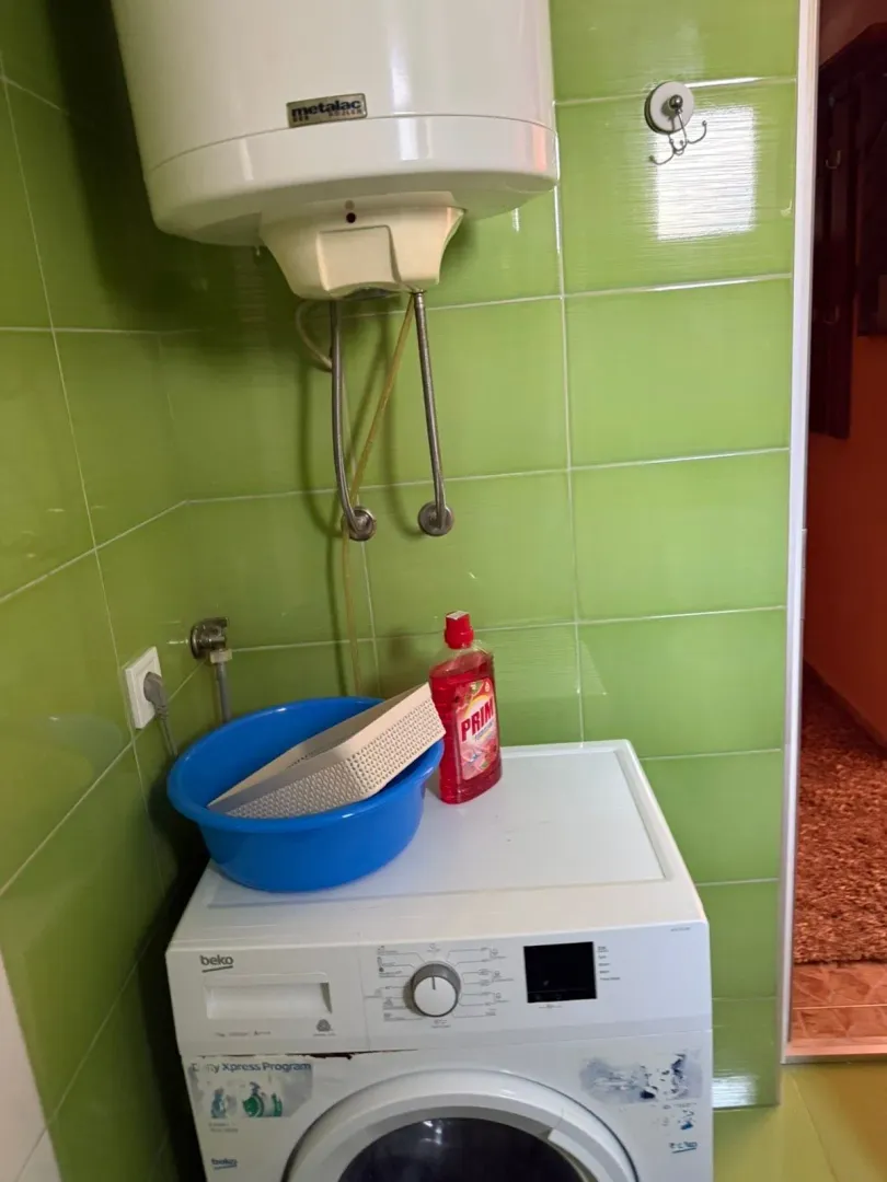 Small bathroom with a washing machine, water heater, and green tiles.