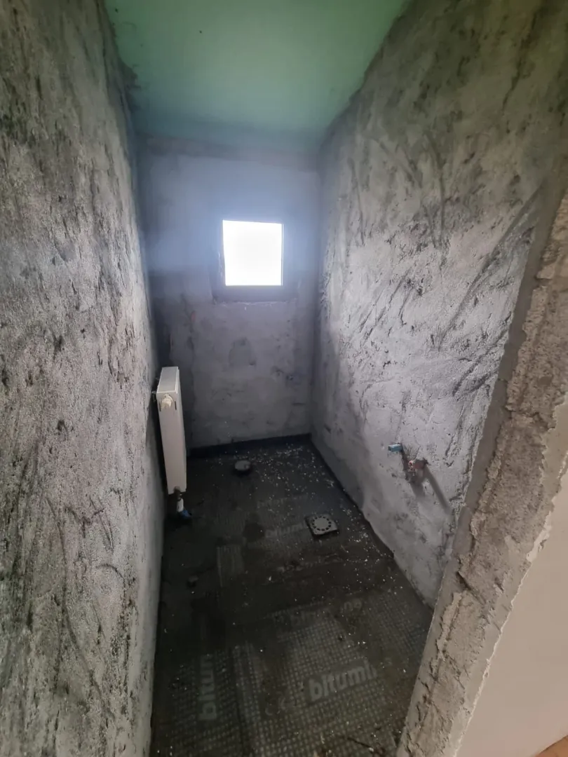 Prostorija u sivoj fazi gradnje sa malim prozorom.