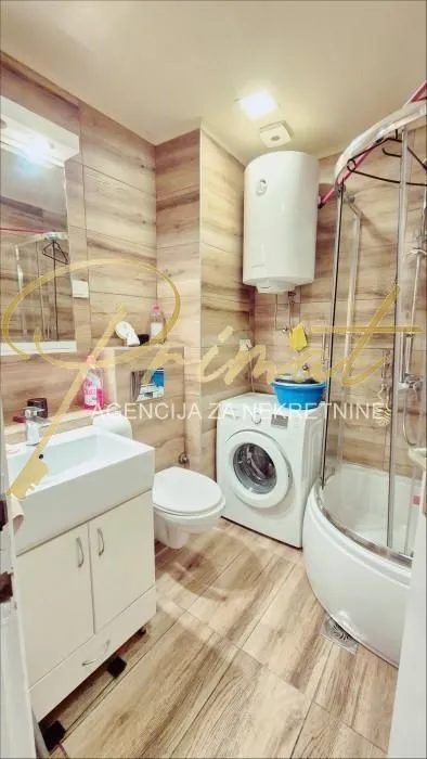 Bathroom equipped with a shower cabin, sink, toilet, and washing machine.