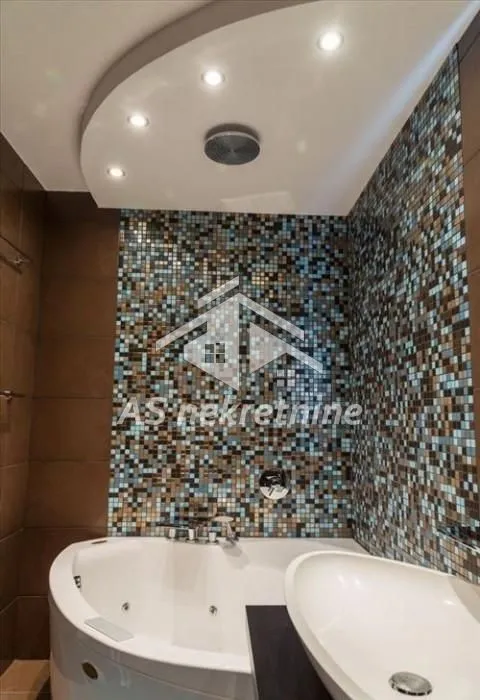 Bathroom with corner bathtub, washbasin, and mosaic tiles.