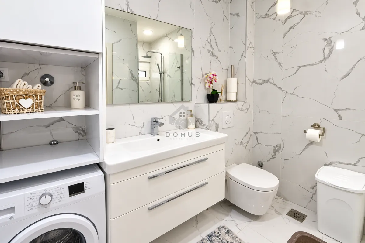 Modern equipped bathroom with a washbasin, toilet, and washing machine.