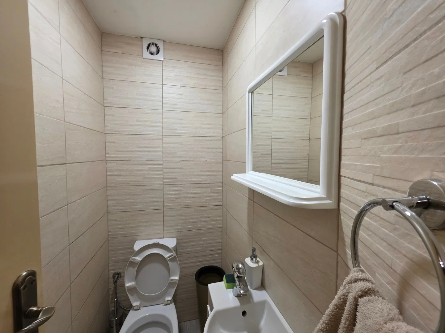 Small bathroom with a toilet, sink, and mirror.