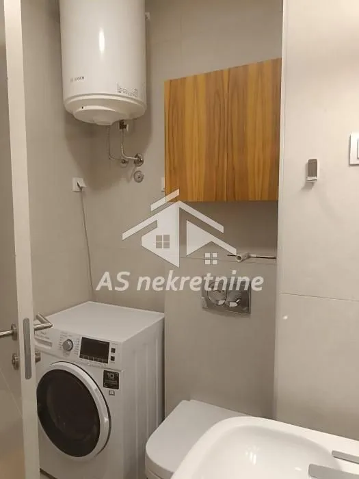 Manje kupatilo sa veš mašinom, bojlerom i sanitarijama.
