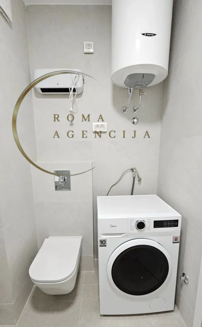 Savremeno opremljeno kupatilo sa WC šoljom, veš mašinom i bojlerom.