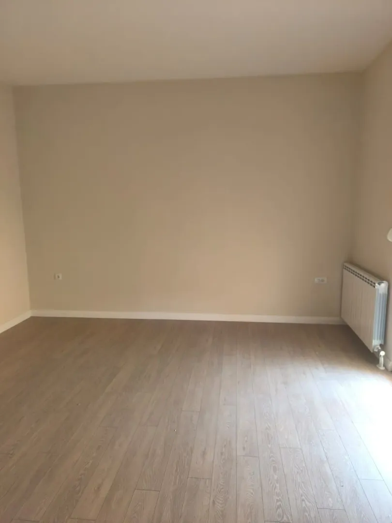 Empty room with laminate flooring and radiator.