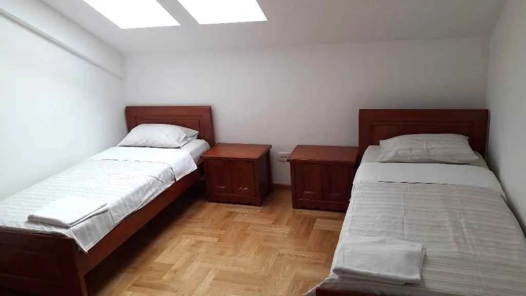 Spavaća soba sa dva singl kreveta i drvenim namještajem.