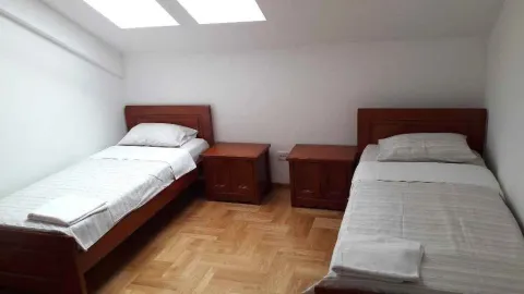 Spavaća soba sa dva singl kreveta i drvenim namještajem. - image 6