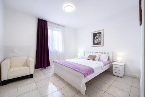 Bedroom with a double bed, white bedside tables and an armchair. - image 6