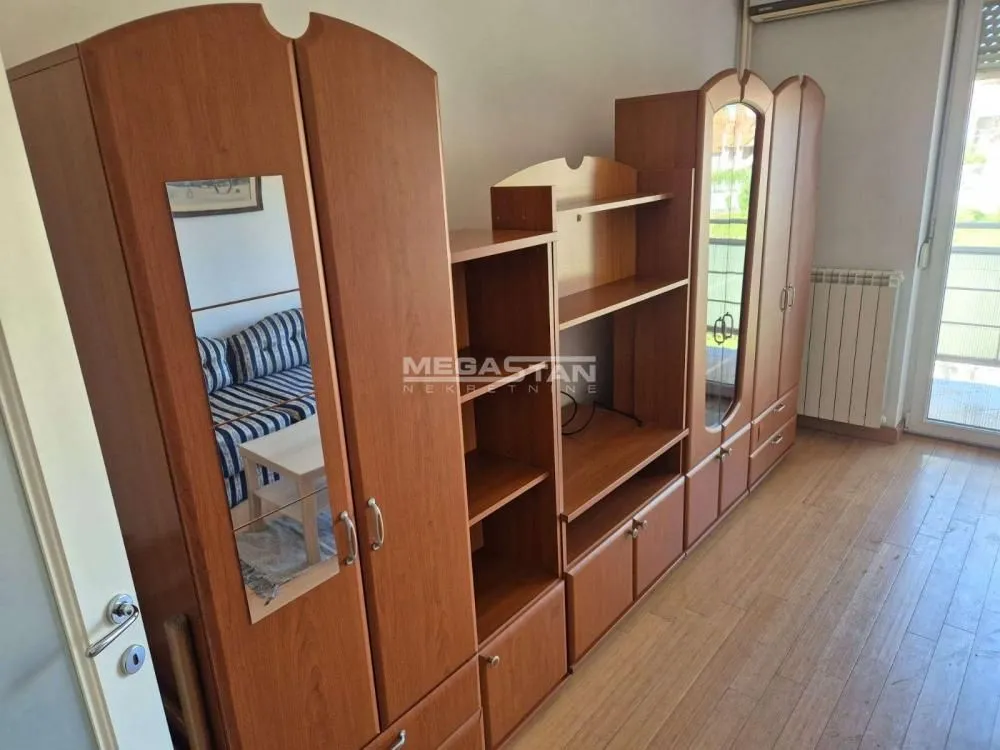 Dnevna soba sa velikim drvenim ormarima i izlazom na terasu.