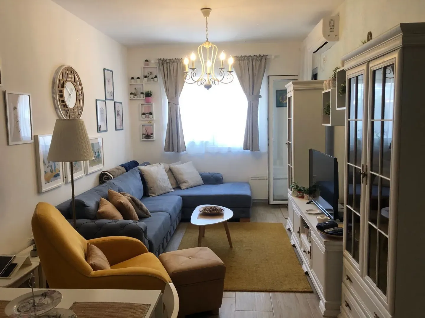 Living room with a sectional sofa, armchair, and TV unit.