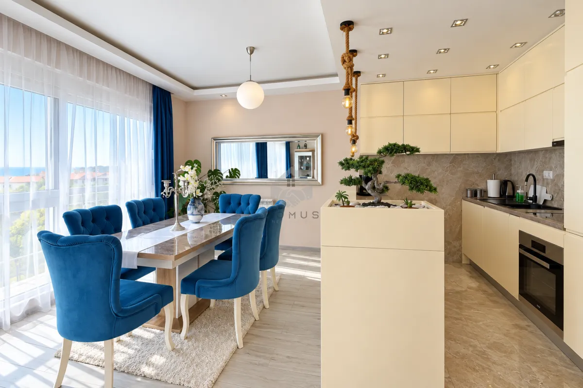 Living room with dining area and kitchen in light tones and blue chairs.