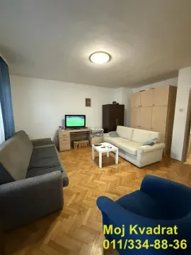 Nameštena dnevna soba sa garniturom, televizorom i parketom na podu. - image 2