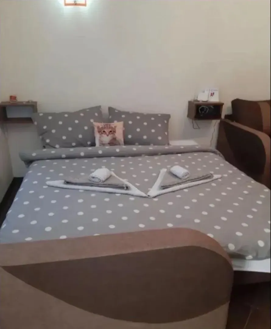 Nameštena spavaća soba sa bračnim krevetom i noćnim stočićima.