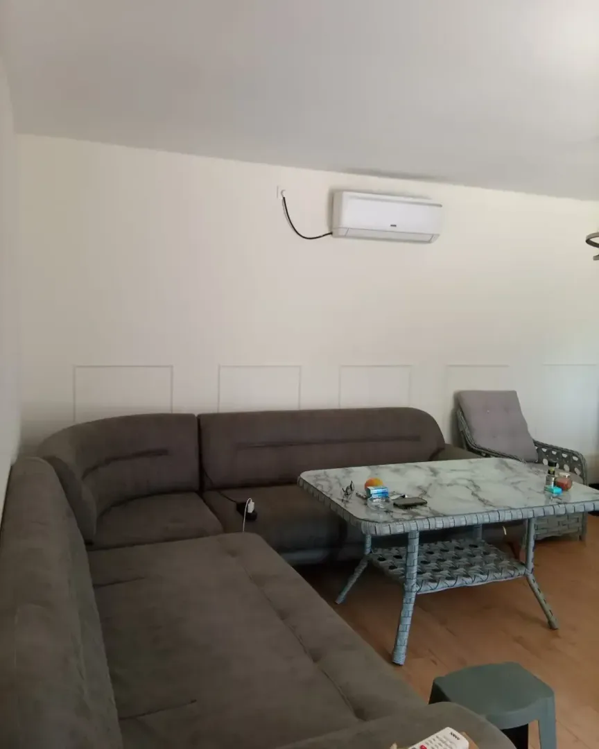 Spacious living room with a sectional sofa, table, and air conditioning unit.