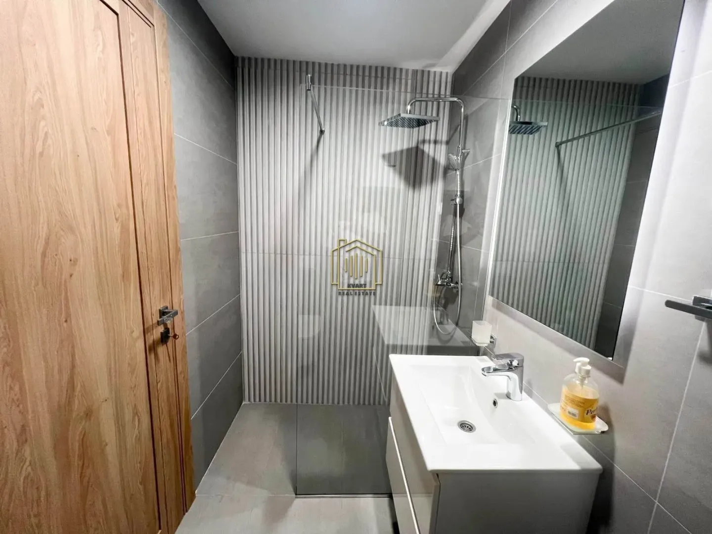 Modern bathroom with walk-in shower, washbasin, and mirror.