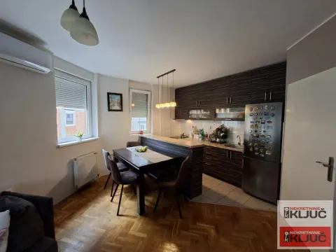 Kuhinja sa trpezarijom i tamnim drvenim elementima. - image 3