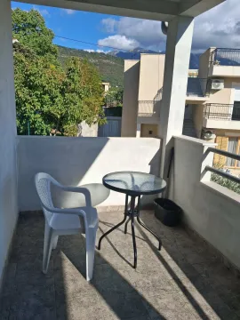Natkrivena terasa sa stolom, stolicom i pogledom na okolne zgrade i brda. - image 3