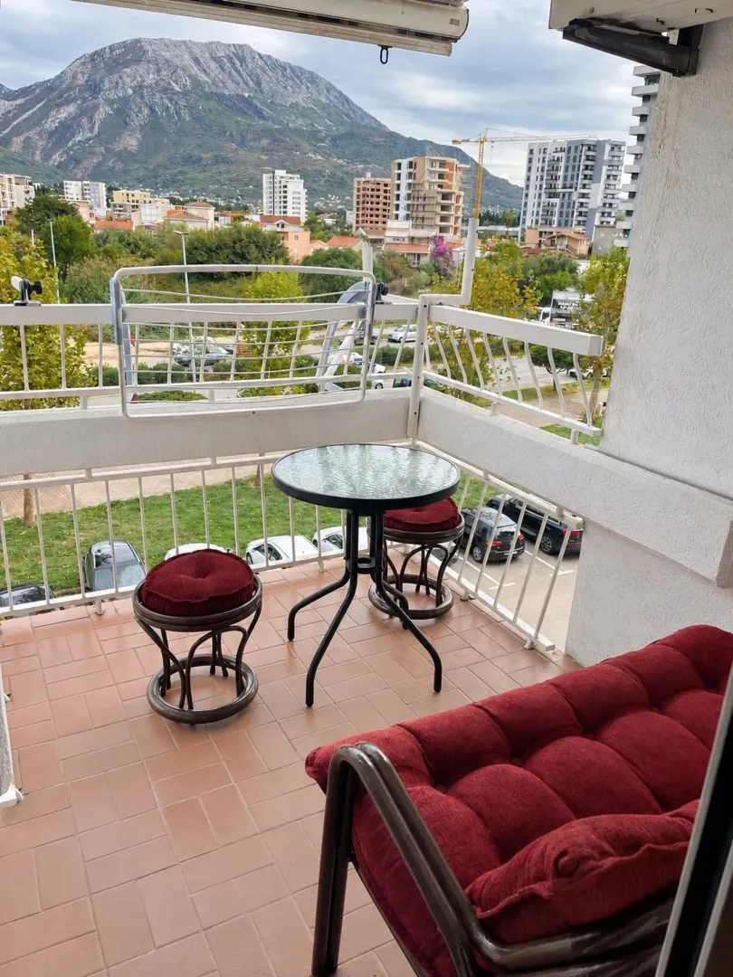 Furnished balcony with seating set and city and mountain views.