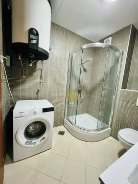 Bathroom equipped with a shower cabin, water heater, and washing machine. - image 8