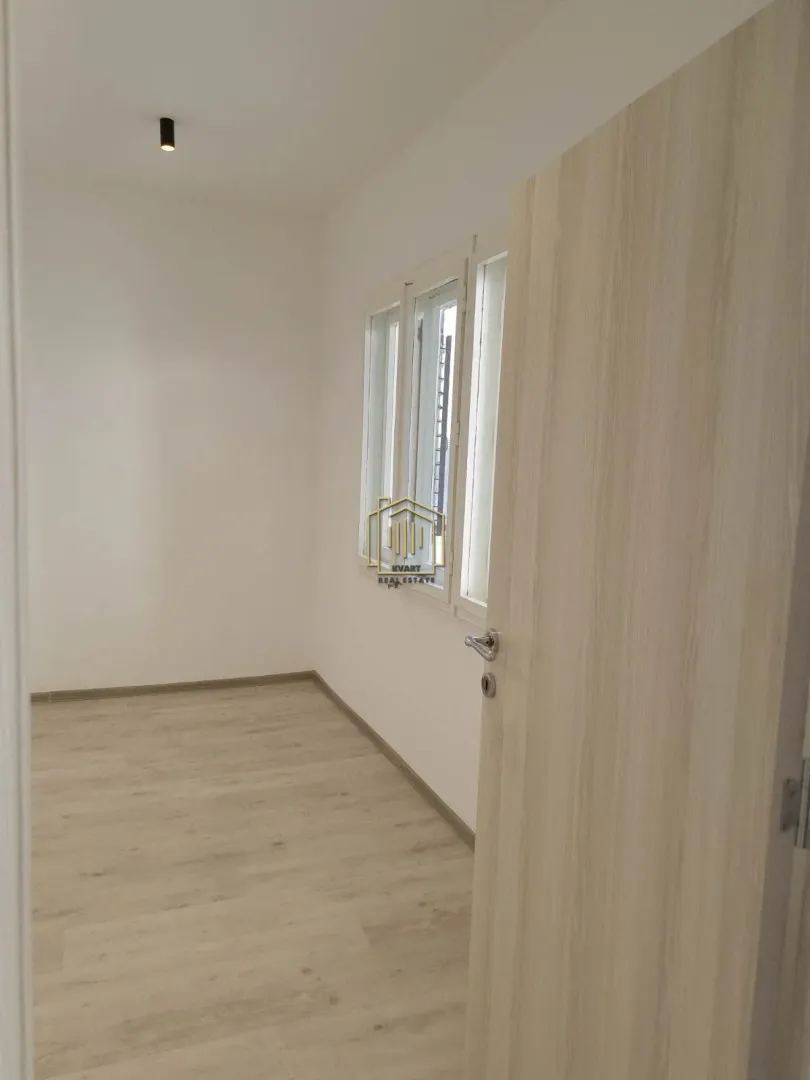 Empty room with light laminate flooring and an open door.