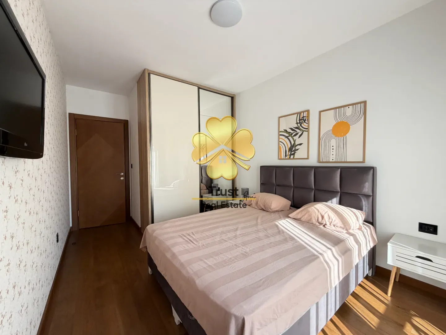 Furnished bedroom with a double bed, wardrobe, and framed pictures on the wall.