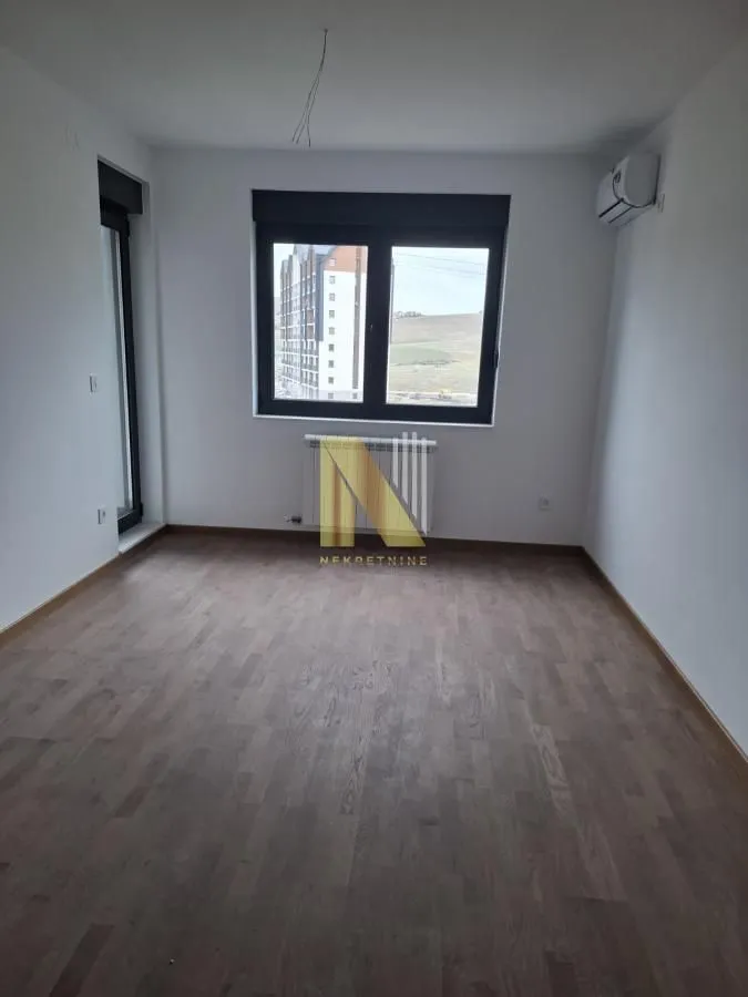 Prazna soba sa parketom i prozorom.