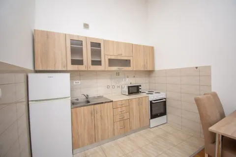 Manja kuhinja sa drvenim elementima, frižiderom i šporetom. - image 3