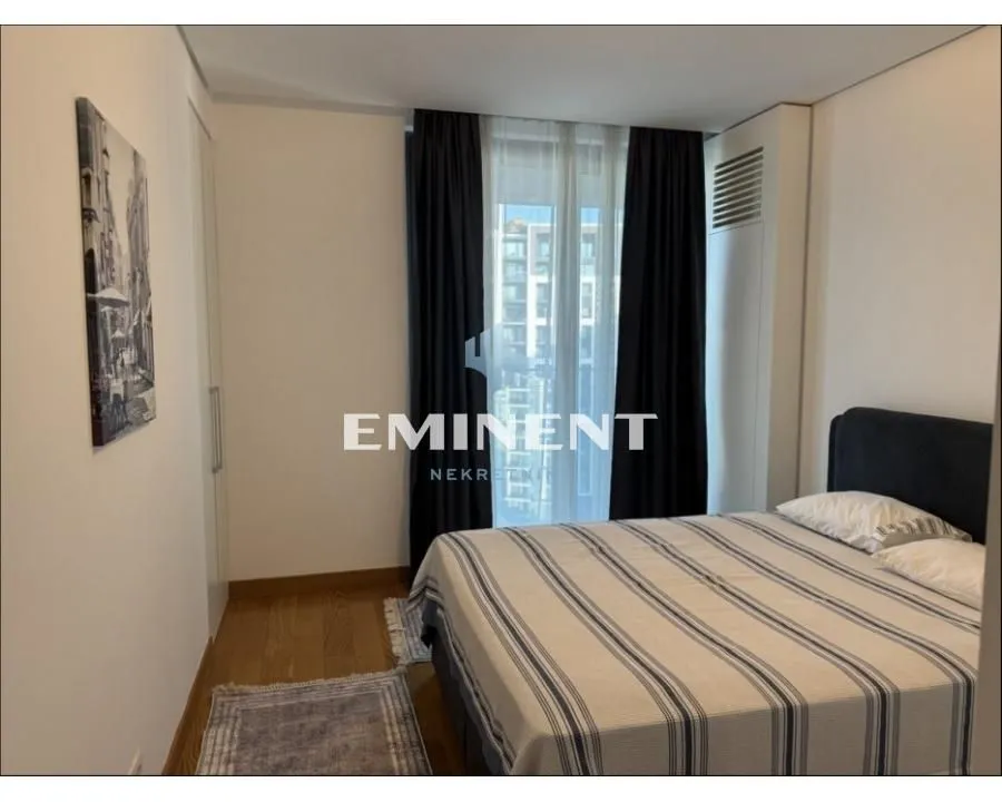 Furnished bedroom with a double bed, wardrobe, and a window with dark curtains.