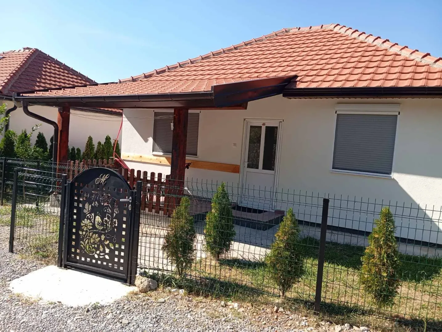 Exterior view of a ground-level house with a landscaped yard and fence.