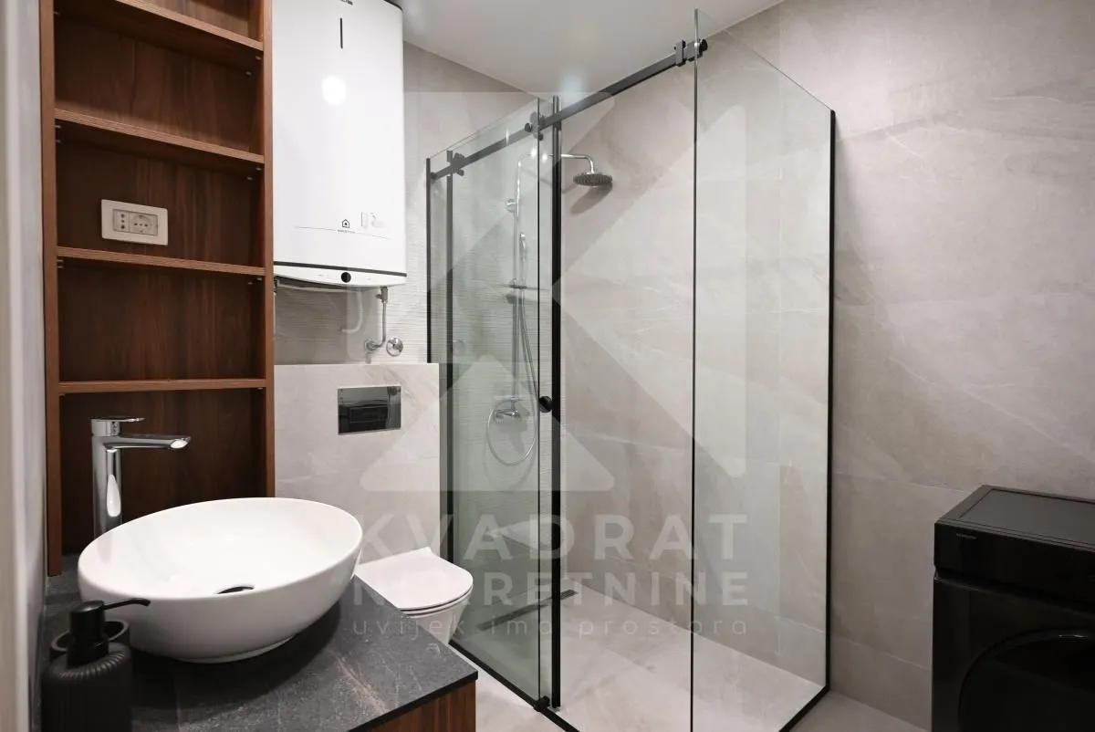Modern bathroom with a walk-in shower, washbasin, and a built-in water heater.