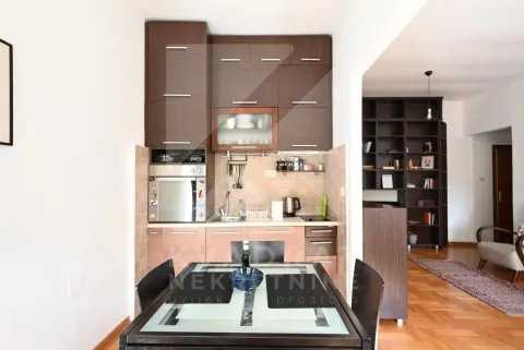 Small kitchen with dark wooden units and a dining table in the foreground. - image 8