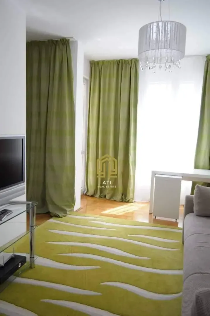 Dnevna soba sa garniturom, zelenim zavjesama i tepihom.
