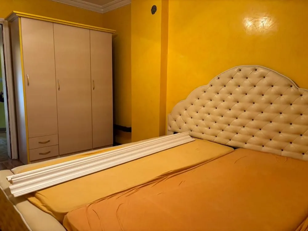 Bedroom with a double bed and a wardrobe against yellow walls.