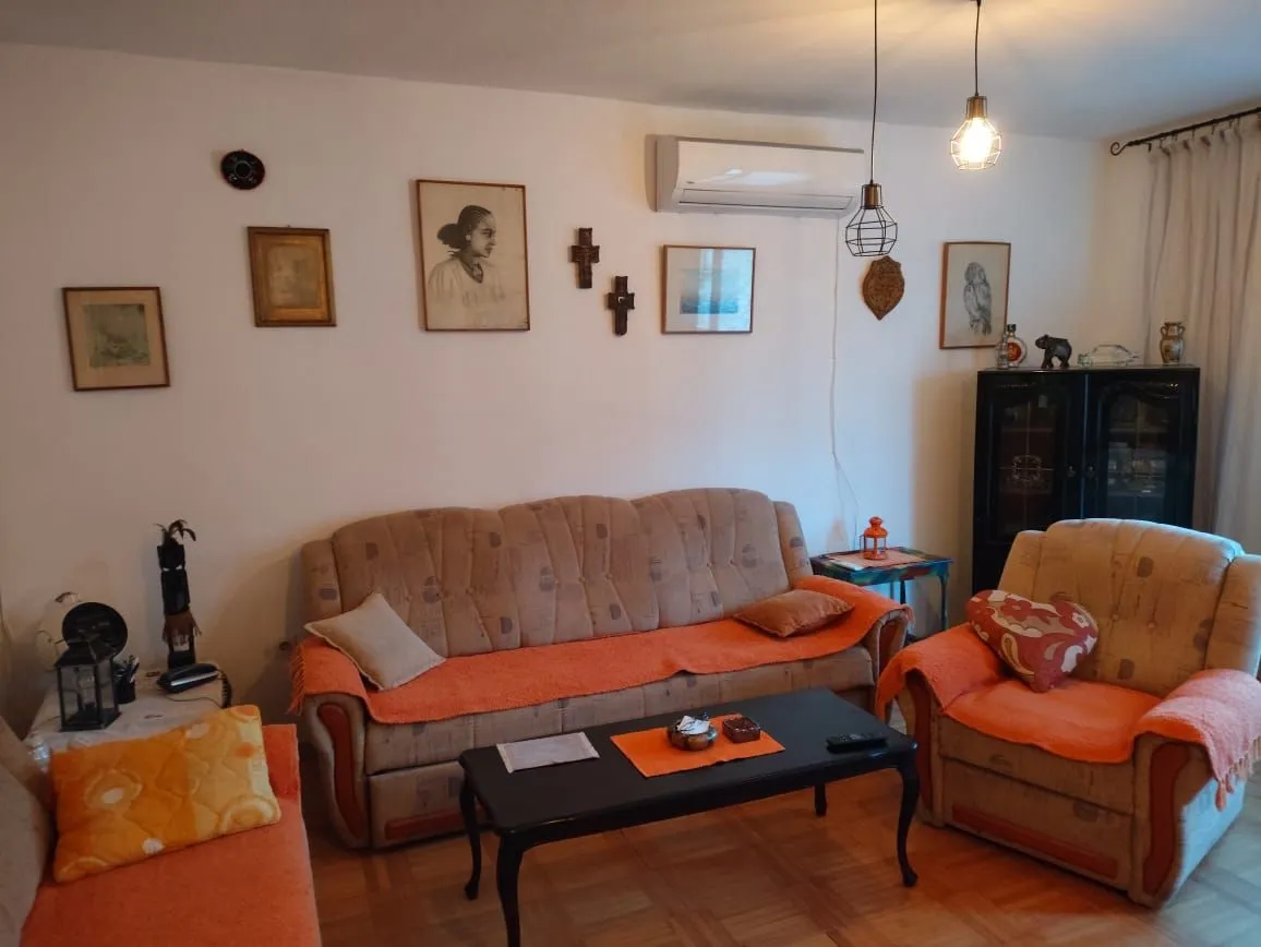 Dnevna soba sa garniturom za sedenje, stočićem i ukrasnim slikama na zidu.