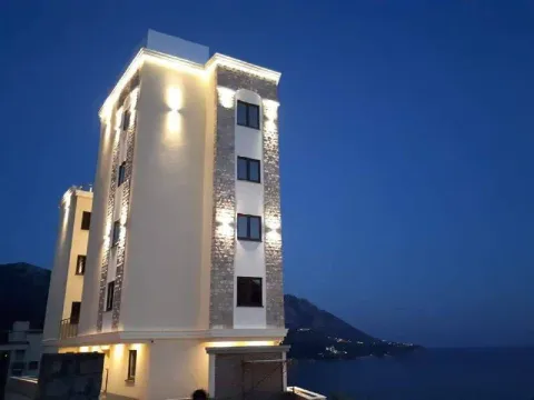 Pogled na osvijetljenu fasadu zgrade noću sa pogledom na more. - image 13