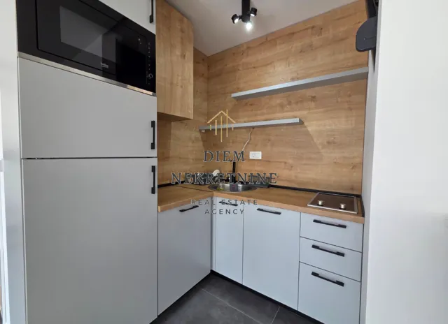 Small modern kitchen with white cabinets and wooden panels.