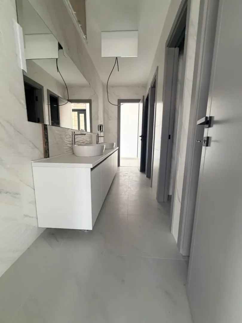Modern bathroom with two washbasins and a large mirror.