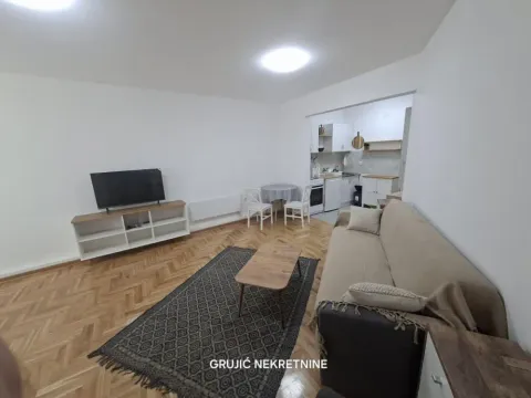 Living room with sofa, TV, and a view of the kitchen in the background. - image 4
