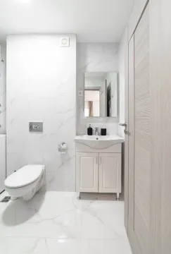 Moderne svetlo kupatilo sa belim pločicama, umivaonikom i toaletom. - image 8