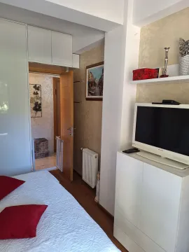 Spavaća soba sa krevetom, bijelim plakarom i televizorom na komodi. - image 11