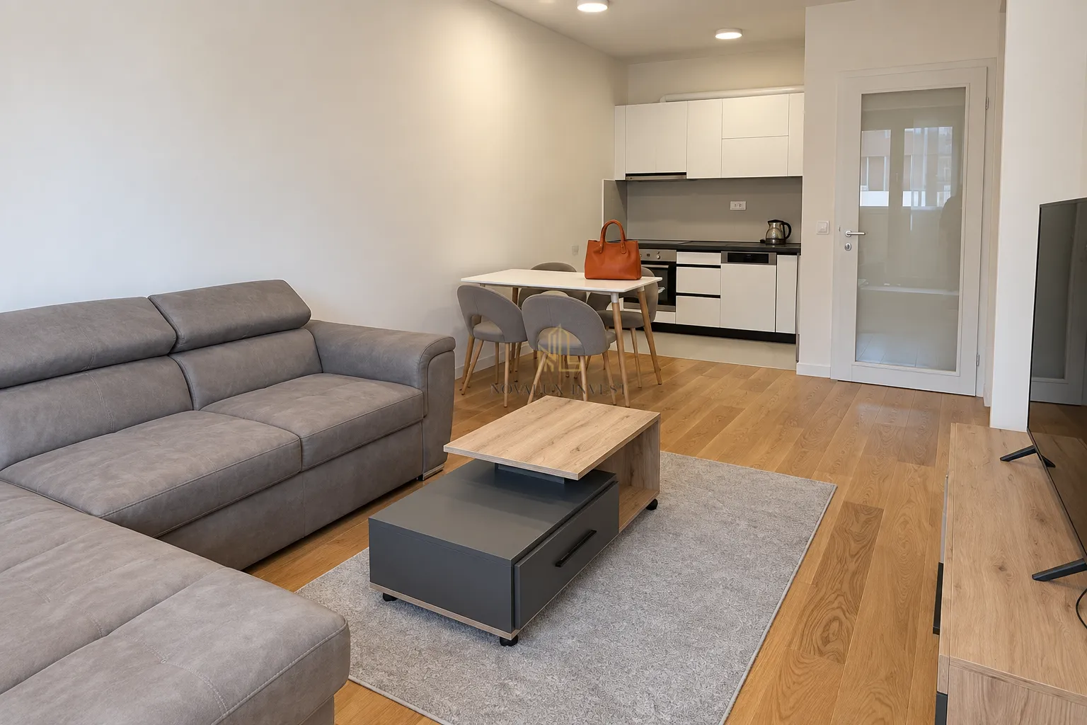 Living room with a sofa, dining area, and kitchen in the background.