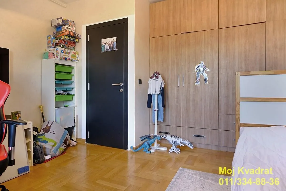 Dečja soba sa krevetom, drvenim ormanom i igračkama.